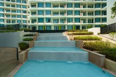a swimming pool with stairs in front of a building at Family 2 Bdr Suite in La Vita Rawai in Rawai Beach