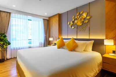 a bedroom with a large white bed with yellow pillows at Family 2 Bdr Suite in La Vita Rawai in Rawai Beach