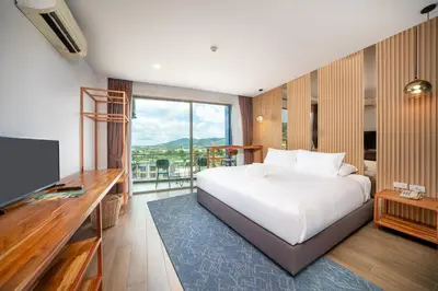 a hotel room with a bed and a television at The Blue Hotel in Chalong