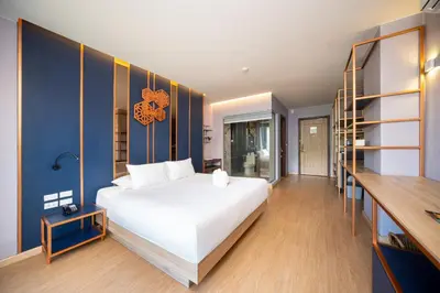 a bedroom with a large white bed and blue walls at The Blue Hotel in Chalong