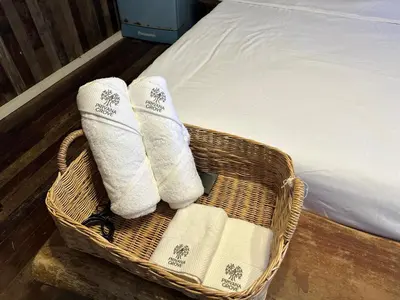 a wicker basket with towels on a bed at Cashew Garden House in Chalong