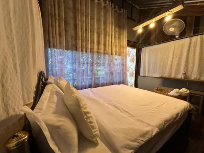 a bedroom with a white bed with a window at Cashew Garden House in Chalong