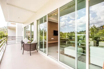 an empty balcony with glass walls and a television at Bangtao Tropical Residence Resort and Spa in Surin Beach