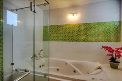 a bathroom with a tub and a glass shower at Bangtao Tropical Residence Resort and Spa in Surin Beach
