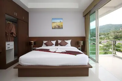 a bedroom with a large bed and a large window at Bangtao Tropical Residence Resort and Spa in Surin Beach