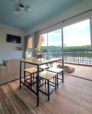 a living room with a table and chairs and a large window at Aonang Riverside Home in Ban Khlong Son