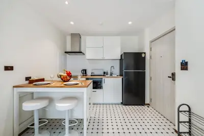 a kitchen with white cabinets and a black refrigerator at Квартира в The Title Halo 1 in Nai Yang Beach
