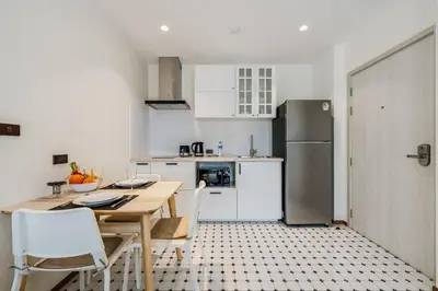 a kitchen with a table and chairs and a refrigerator at Квартира в The Title Halo 1 in Nai Yang Beach