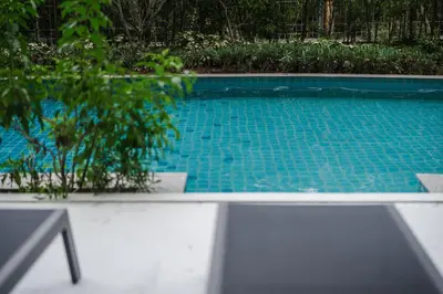 a blue swimming pool with a table and a plant at Квартира в The Title Halo 1 in Nai Yang Beach