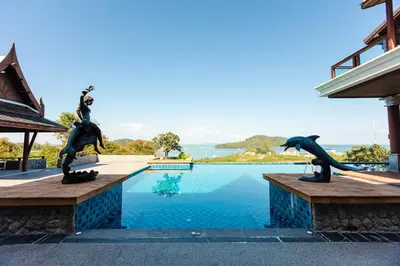 a swimming pool with two bronze dolphins statues next to a house at Grand View Panwa Luxury Villa in Ban Ao Makham