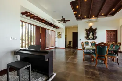 a living room with a piano and a table with chairs at Grand View Panwa Luxury Villa in Ban Ao Makham