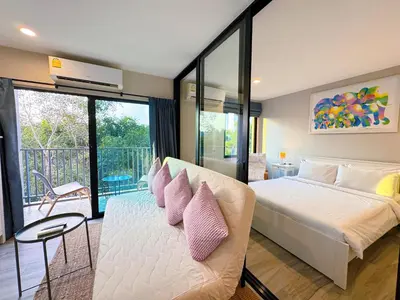 a bedroom with a large bed with pink pillows at Digital Nomad Home Away With Pool & Gym in Nai Yang Beach