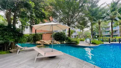 an umbrella and a chair next to a swimming pool at Digital Nomad Home Away With Pool & Gym in Nai Yang Beach