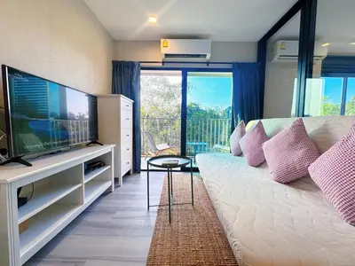 a living room with a couch and a large television at Digital Nomad Home Away With Pool & Gym in Nai Yang Beach