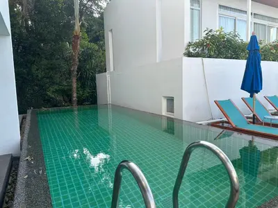 a swimming pool with chairs and an umbrella at Jirana Patong in Patong Beach