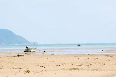 a boat sitting on a beach with the ocean at CHEZ MAURICE A RAWAIi in Rawai Beach