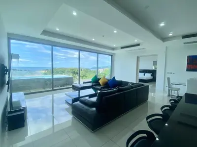 a living room with a black couch and a large window at The View Condominium 360 m2 Sea View Penthouse in Kata Beach