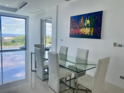 a dining room with a glass table and white chairs at The View Condominium 360 m2 Sea View Penthouse in Kata Beach