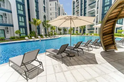 a swimming pool with chairs and an umbrella next to a pool at Title Halo, 2 bedrooms apartment in Nai Yang Beach