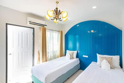 two beds in a bedroom with a blue headboard at Home in Phuket in Ban Phlu Yai