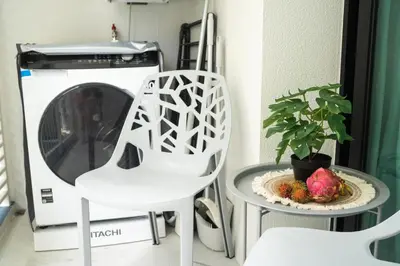 a laundry room with a washing machine and two white chairs at Paradise Bird in Nai Yang Beach