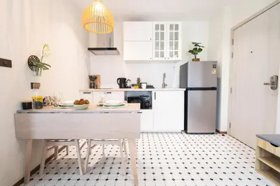 a white kitchen with a refrigerator and a table at Paradise Bird in Nai Yang Beach