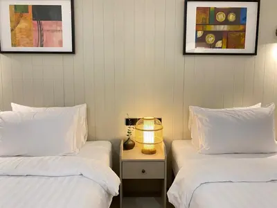 two beds with white sheets and a lamp on a night stand at Sea Breeze Villa Patong in Patong Beach