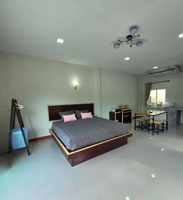 a bedroom with a bed and a table in it at Aonang Riverside Home in Ban Khlong Son