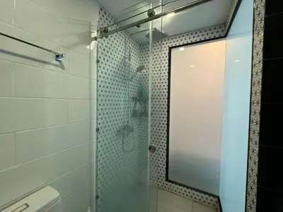 a bathroom with a glass shower with a mirror at Royal Lee Condo in Ban Bo Han