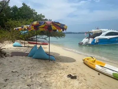 a beach with an umbrella and a boat in the water at Naturist Beach Camping Private Beach Phuket in Ko Lone