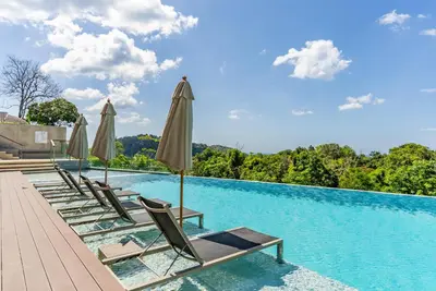 a swimming pool with lounge chairs and umbrellas at Bluepoint by Villacarte in Patong Beach
