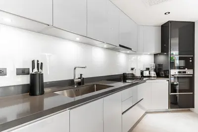 a kitchen with white cabinets and a stainless steel sink at Bluepoint by Villacarte in Patong Beach