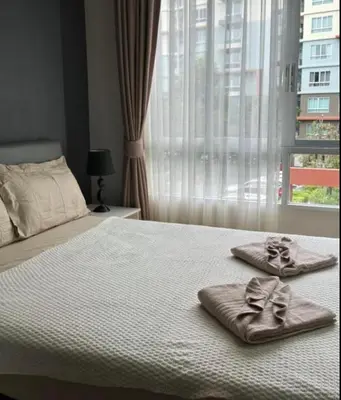 a bed with two towels on it with a window at Lux Center Apartment in Kathu