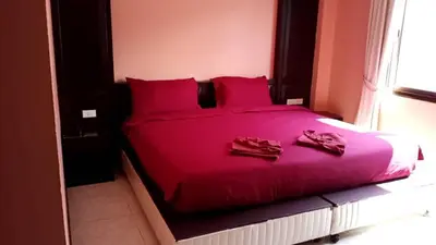 a red bed with red pillows and shoes on it at Sumer guesthouses in Patong Beach