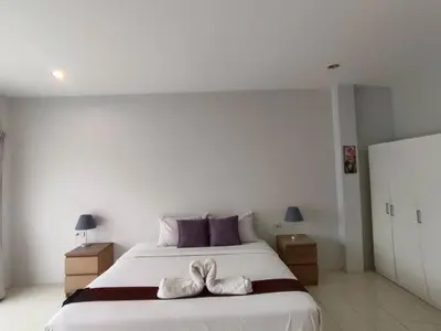 a bedroom with a large bed with two white towels on it at Sunshine Guesthouse Nanai Patong in Patong Beach