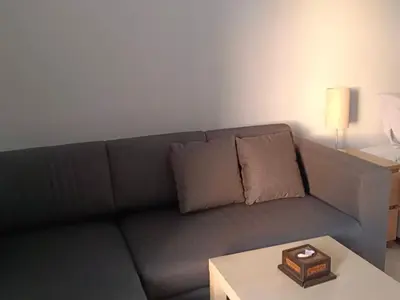 a living room with a gray couch and a table at Sunshine Guesthouse Nanai Patong in Patong Beach