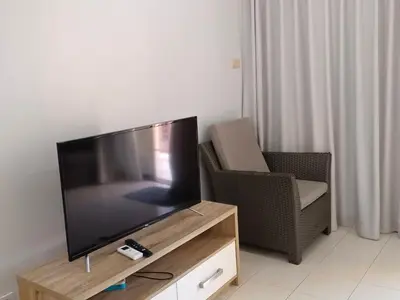 a flat screen tv sitting on top of a wooden entertainment center at Sunshine Guesthouse Nanai Patong in Patong Beach
