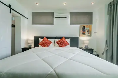 a bedroom with a large white bed with red pillows at Skyfall Private Pool Villa In Rawai in Rawai Beach