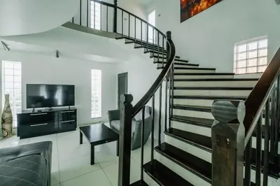 a spiral staircase in a living room with a television at Skyfall Private Pool Villa In Rawai in Rawai Beach