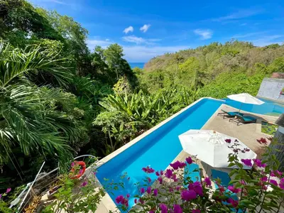 a pool with a view of the jungle and flowers at Kata Seaview Serenity - Luxury 1BR Apartment in Karon Beach