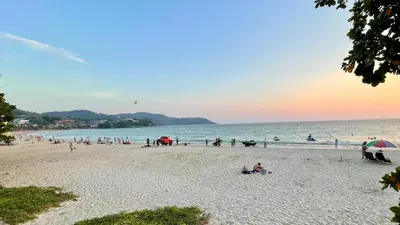 a group of people on the beach at sunset at Kata Seaview Serenity - Luxury 1BR Apartment in Karon Beach