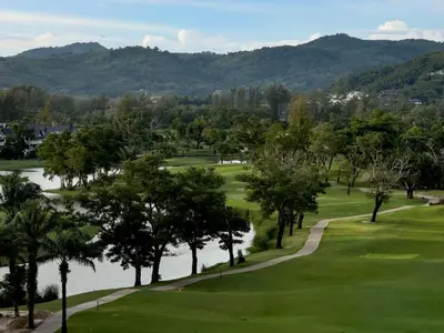 a view of a golf course with a lake and mountains at Skypark by Villacarte in Laguna Phuket