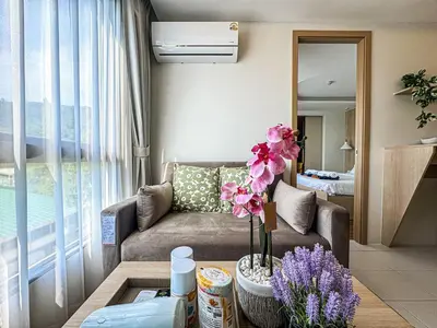 a living room with a couch and flowers on a table at New 1BDR Fantasea Kamala beach in Kamala Beach