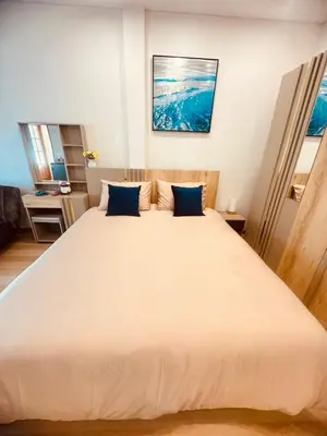 a bedroom with a large white bed with blue pillows at Baannira บ้านนิรา in Ban Sam Kong