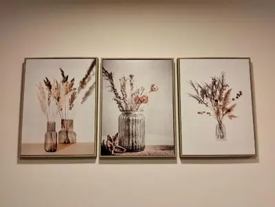 four pictures of vases with flowers in them on a wall at Baannira บ้านนิรา in Ban Sam Kong