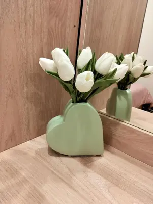 a green heart vase with white flowers in it at Baannira บ้านนิรา in Ban Sam Kong