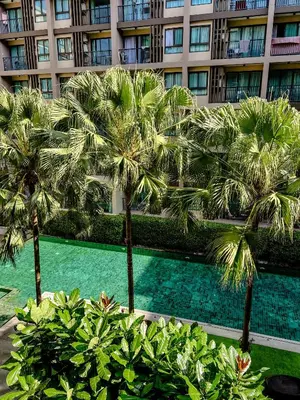 a building with palm trees in front of a swimming pool at Central Pool in Ban Lo Long