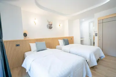 two beds in a hotel room with white sheets at Phunaya Phuket Oldtown Hotel in Phuket Town