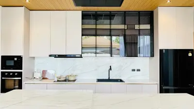 a kitchen with white cabinets and a black refrigerator at Mouana Residence Song Khun Chalong 8910 in Phuket Town