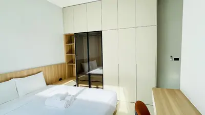 a bedroom with a white bed and a table at Mouana Residence Song Khun Chalong 8910 in Phuket Town